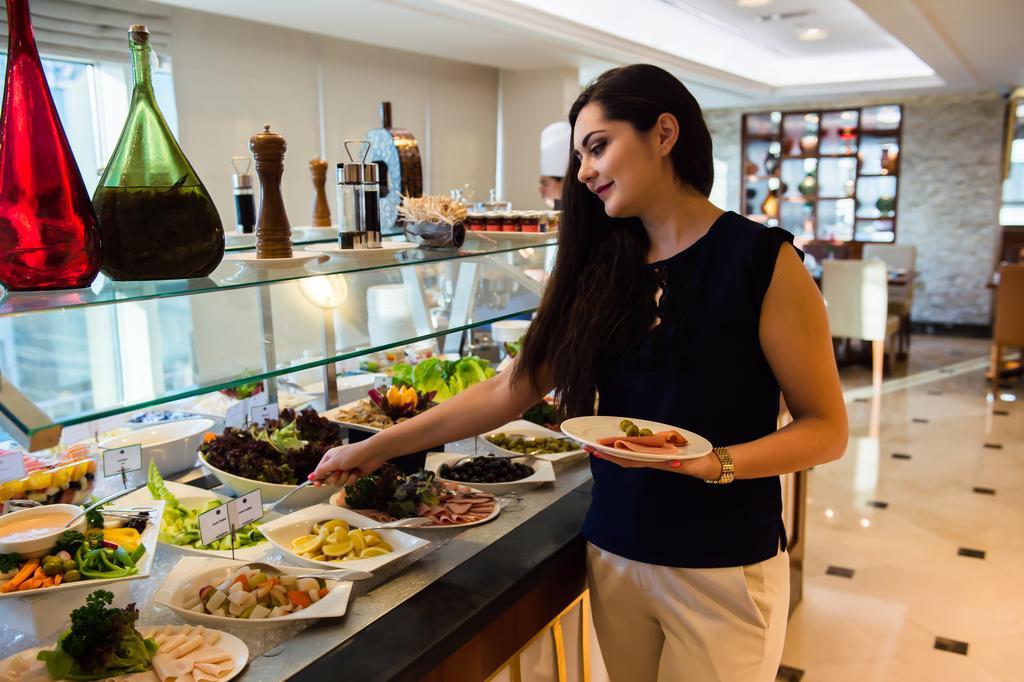 Grand Mercure Majlis Residences Abu Dabi Dış mekan fotoğraf A woman selecting food from a buffet